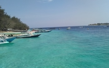 Sunset at Gili Trawangan beach, golden sky over calm ocean, Lombok island paradise Indonesia.